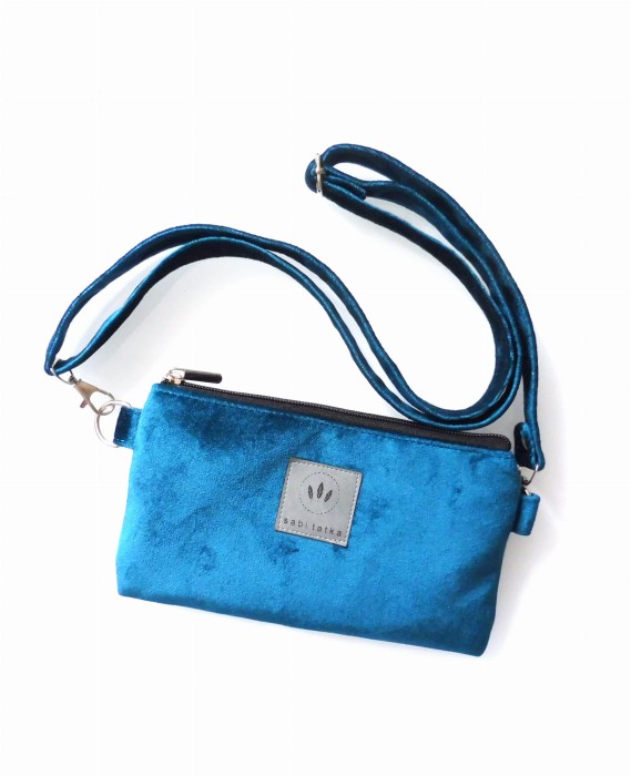 Welurowa saszetka na telefon w kolorze turkusowym, noszona na skos. Miękka faktura, kompaktowy kształt i regulowany pasek czynią ją idealną na spacer, miasto i podróże. Stylowa i praktyczna.