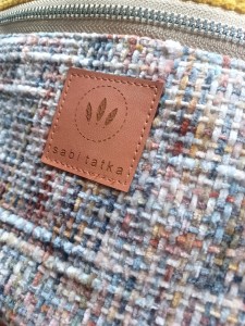 Torebka nerka damska w miejskim wydaniu. Wykonana z tkaniny tweedowej w pastelowej kolorystyce, z kontrastowymi akcentami w odcieniach błękitu i musztardowej żółci. Idealna jako nerka przez ciało – świetny wybór do casualowych i miejskich stylizacji.