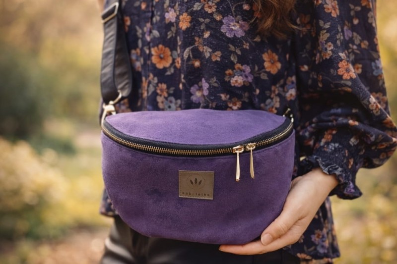Fioletowa zamszowa nerka damska o eleganckim, minimalistycznym designie. Miękka w dotyku, z regulowanym paskiem i solidnym zamkiem. Idealna na co dzień i do stylizacji casual oraz lifestyle.