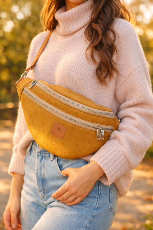 Stylowa nerka XL z nubuku w ciepłym miodowym odcieniu. Miękka, trwała faktura, modny półokrągły kształt i regulowany pasek. Idealna do miejskich i casualowych stylizacji, łączy funkcjonalność z nowoczesnym designem.