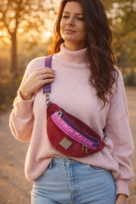 Kolorowa welurowa nerka o modnym półokrągłym kształcie, z regulowanym paskiem. Miękka faktura, bordowy kolor z różowymi akcentami i praktyczne kieszenie czynią ją stylowym dodatkiem lifestyle na co dzień.