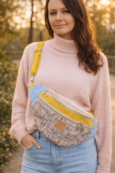 Torebka nerka damska w miejskim wydaniu. Wykonana z tkaniny tweedowej w pastelowej kolorystyce, z kontrastowymi akcentami w odcieniach błękitu i musztardowej żółci. Idealna jako nerka przez ciało – świetny wybór do casualowych i miejskich stylizacji.