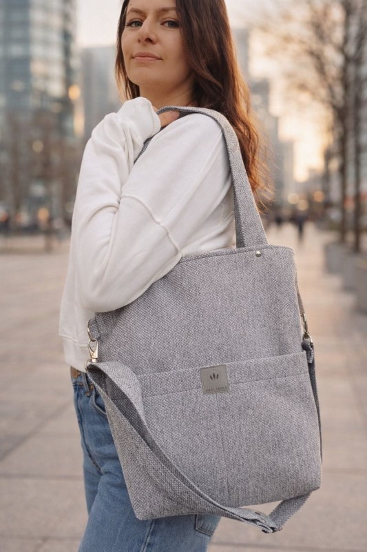 Nowoczesna, szara torebka shopper z wytrzymałej tkaniny, idealna do codziennego użytku. Minimalistyczny design, pojemne wnętrze i wygodne paski sprawiają, że doskonale pasuje do miejskich, casualowych stylizacji.