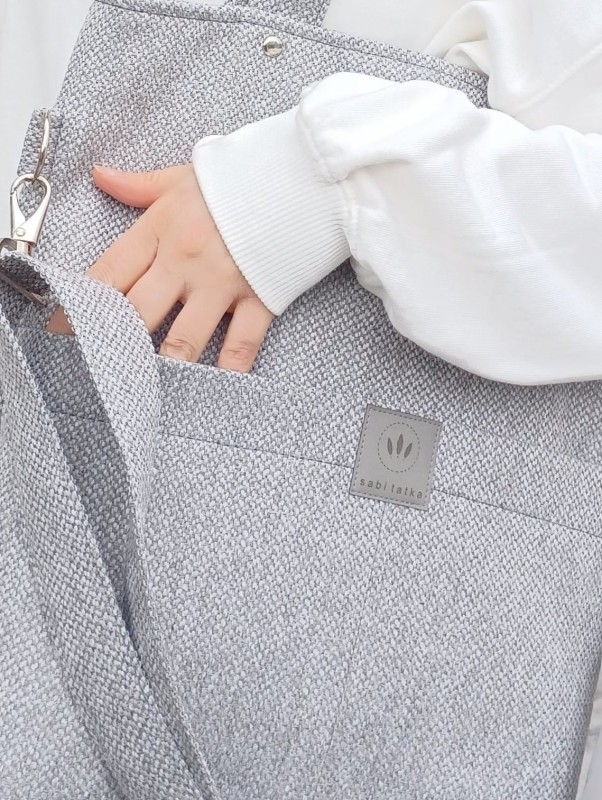 Nowoczesna, szara torebka shopper z wytrzymałej tkaniny, idealna do codziennego użytku. Minimalistyczny design, pojemne wnętrze i wygodne paski sprawiają, że doskonale pasuje do miejskich, casualowych stylizacji.