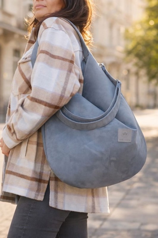 Zamszowa torba hobo w eleganckim, miejskim stylu. Miękka, lekka i pojemna, idealna na co dzień. Ponadczasowy kształt, naturalna faktura zamszu i wygodne noszenie na ramieniu. Stylowa torba damska do miasta.