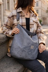 Zamszowa torba hobo w eleganckim, miejskim stylu. Miękka, lekka i pojemna, idealna na co dzień. Ponadczasowy kształt, naturalna faktura zamszu i wygodne noszenie na ramieniu. Stylowa torba damska do miasta.