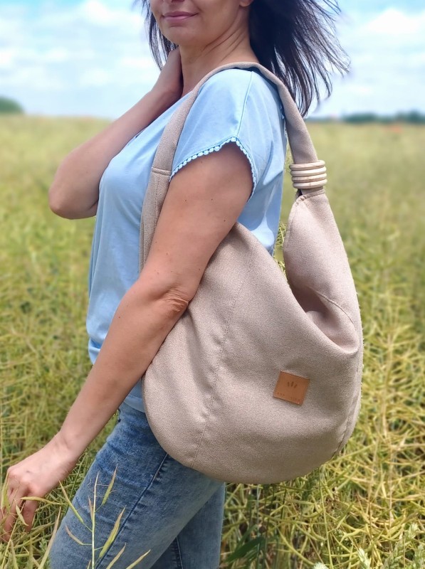 Torba worek z lnianej plecionki o miękkiej, naturalnej fakturze. Lekka, pojemna i wygodna, idealna na co dzień. Subtelny, minimalistyczny design w neutralnym kolorze pasuje do stylizacji casual i boho.