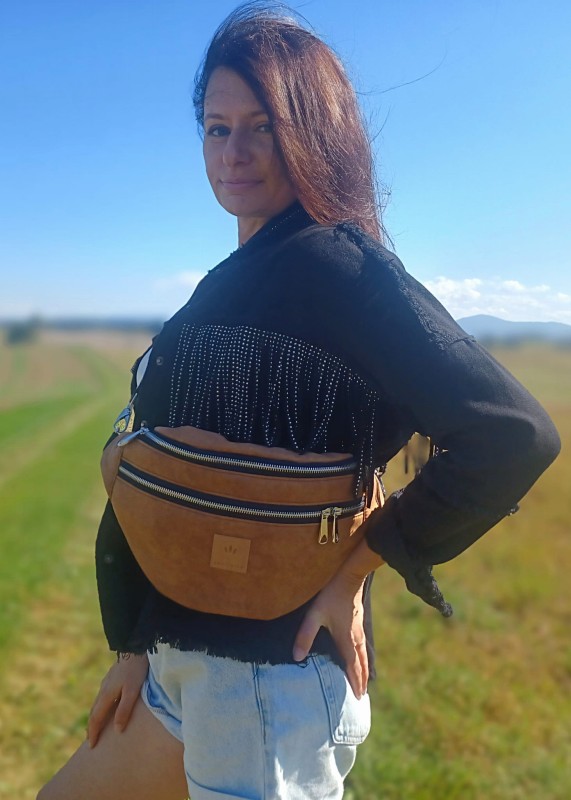 Duża nerka z naturalnego zamszu w kolorze brązowym karmelowym. Stylowa, pojemna i wygodna, z podwójnym zamkiem i regulowanym paskiem. Idealna do codziennych stylizacji i looków lifestyle.
