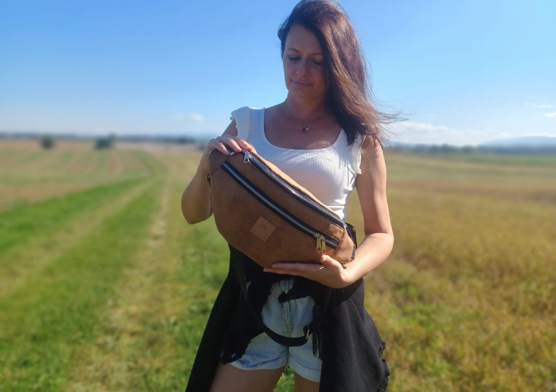 Duża nerka z naturalnego zamszu w kolorze brązowym karmelowym. Stylowa, pojemna i wygodna, z podwójnym zamkiem i regulowanym paskiem. Idealna do codziennych stylizacji i looków lifestyle.