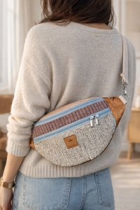 Duża nerka z tweedowej tkaniny w pastelowych kolorach z  regulowanym paskiem. Stylowa, pojemna i wygodna, idealna do miejskich i podróżnych stylizacji casualowych.