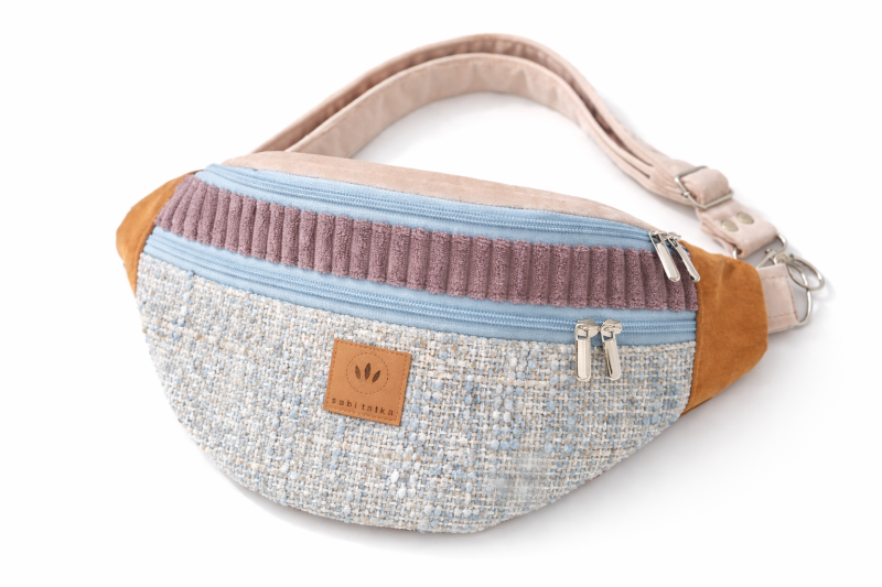 Duża nerka z tweedowej tkaniny w pastelowych kolorach z  regulowanym paskiem. Stylowa, pojemna i wygodna, idealna do miejskich i podróżnych stylizacji casualowych.