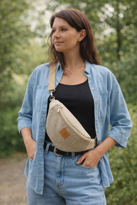 Beżowa nerka w rozmiarze basic, wykonana z przyjemnej w dotyku plecionki i jasnego zamszu. Regulowany pasek i skórzana naszywka z logo nadają jej naturalny, minimalistyczny charakter.