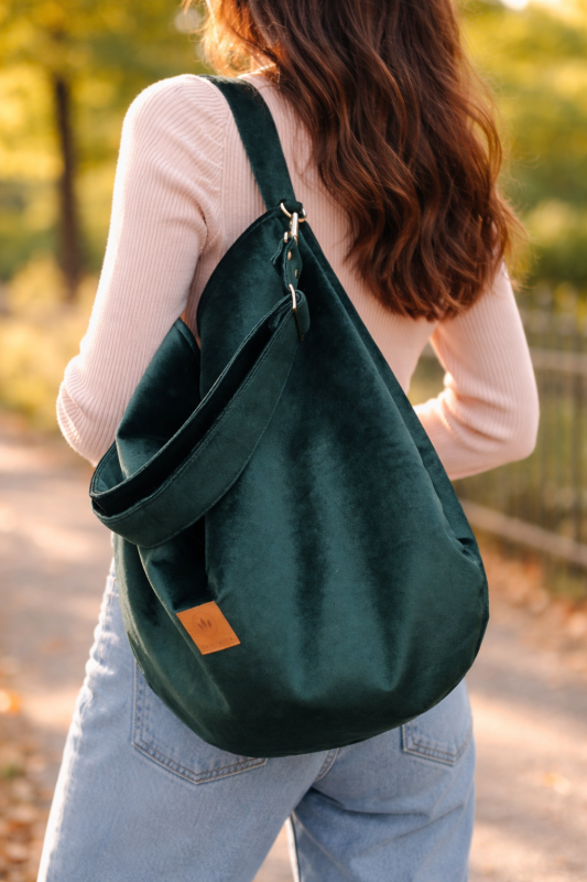 Duża, stylowa torebka w kolorze butelkowej zieleni, wykonana z miękkiego, aksamitnego materiału. Posiada wygodny pasek na ramię, solidne metalowe okucia oraz subtelne logo, idealna do codziennych miejskich stylizacji.