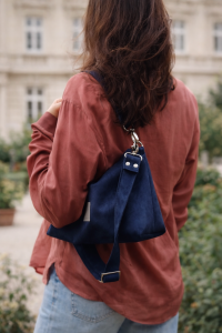 Mała zamszowa torebka w kolorze głębokiego granatu, elegancka i funkcjonalna. Miękka faktura, regulowany pasek i minimalistyczny design sprawiają, że idealnie pasuje do codziennych i eleganckich stylizacji.