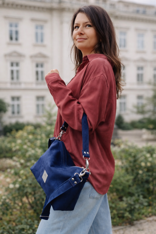 Mała zamszowa torebka w kolorze głębokiego granatu, elegancka i funkcjonalna. Miękka faktura, regulowany pasek i minimalistyczny design sprawiają, że idealnie pasuje do codziennych i eleganckich stylizacji.