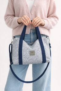 Stylowa torebka z plecionki o eleganckim, prostokątnym kształcie. Jasnoniebieska struktura z granatowymi uchwytami i regulowanym paskiem łączy naturalną fakturę z nowoczesnym designem. Lekka, pojemna i idealna na co dzień.