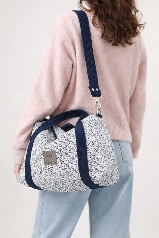 Stylowa torebka z plecionki o eleganckim, prostokątnym kształcie. Jasnoniebieska struktura z granatowymi uchwytami i regulowanym paskiem łączy naturalną fakturę z nowoczesnym designem. Lekka, pojemna i idealna na co dzień.