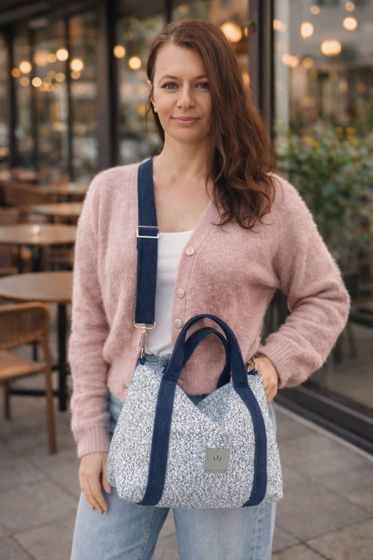 Stylowa torebka z plecionki o eleganckim, prostokątnym kształcie. Jasnoniebieska struktura z granatowymi uchwytami i regulowanym paskiem łączy naturalną fakturę z nowoczesnym designem. Lekka, pojemna i idealna na co dzień.