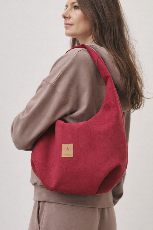 Zamszowa torba hobo w intensywnym czerwonym kolorze to stylowy dodatek do miejskich stylizacji. Miękka, pojemna i wygodna w noszeniu na ramieniu, łączy modny design z funkcjonalnością. Idealna do casualowych i streetwearowych zestawów.