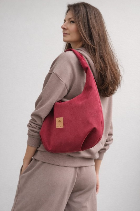Zamszowa torba hobo w intensywnym czerwonym kolorze to stylowy dodatek do miejskich stylizacji. Miękka, pojemna i wygodna w noszeniu na ramieniu, łączy modny design z funkcjonalnością. Idealna do casualowych i streetwearowych zestawów.