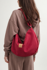 Zamszowa torba hobo w głębokim, czerwonym kolorze. Miękka, pojemna i lekka, z wygodnym paskiem na ramię. Stylowy, półokrągły kształt i minimalistyczny design sprawiają, że idealnie dopełnia miejskie i casualowe stylizacje.