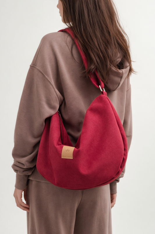 Zamszowa torba hobo w głębokim, czerwonym kolorze. Miękka, pojemna i lekka, z wygodnym paskiem na ramię. Stylowy, półokrągły kształt i minimalistyczny design sprawiają, że idealnie dopełnia miejskie i casualowe stylizacje.