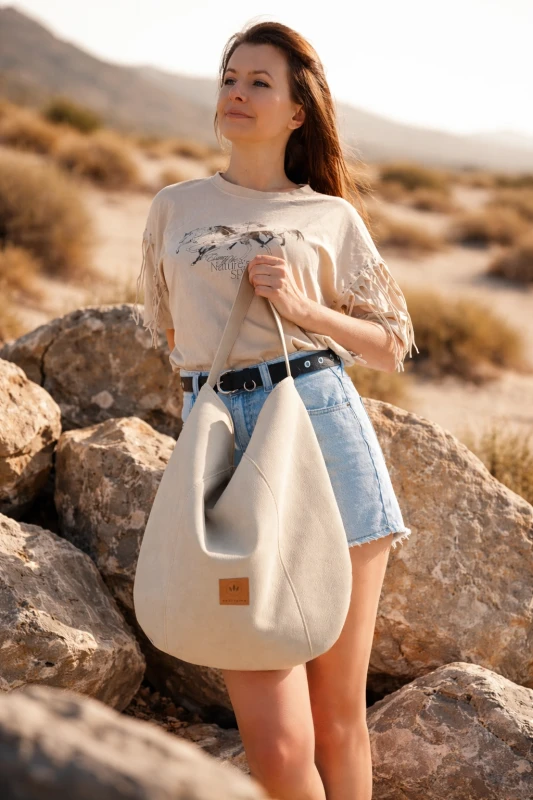 Zamszowa torba hobo w kolorze kremowym– miękka, lekka i stylowa. Pojemna forma, minimalistyczny design i naturalna faktura sprawiają, że idealnie uzupełnia codzienne i letnie stylizacje.