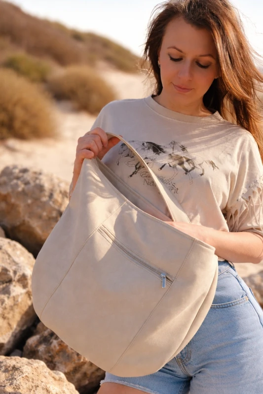Zamszowa torba hobo w kolorze kremowym– miękka, lekka i stylowa. Pojemna forma, minimalistyczny design i naturalna faktura sprawiają, że idealnie uzupełnia codzienne i letnie stylizacje.