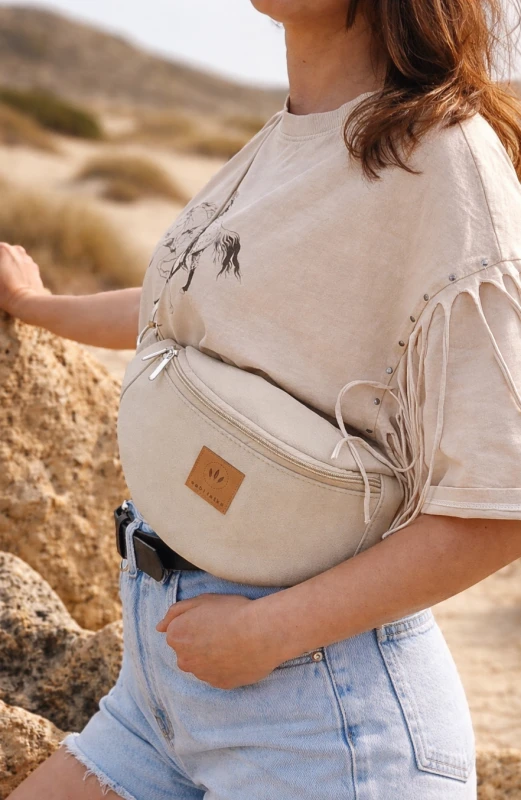 Kremowa zamszowa nerka damska – elegancka, miękka i funkcjonalna. Idealna na co dzień i podróże, łączy styl z wygodą. Regulowany pasek, modny fason i wysokiej jakości materiał podkreślą każdą stylizację.