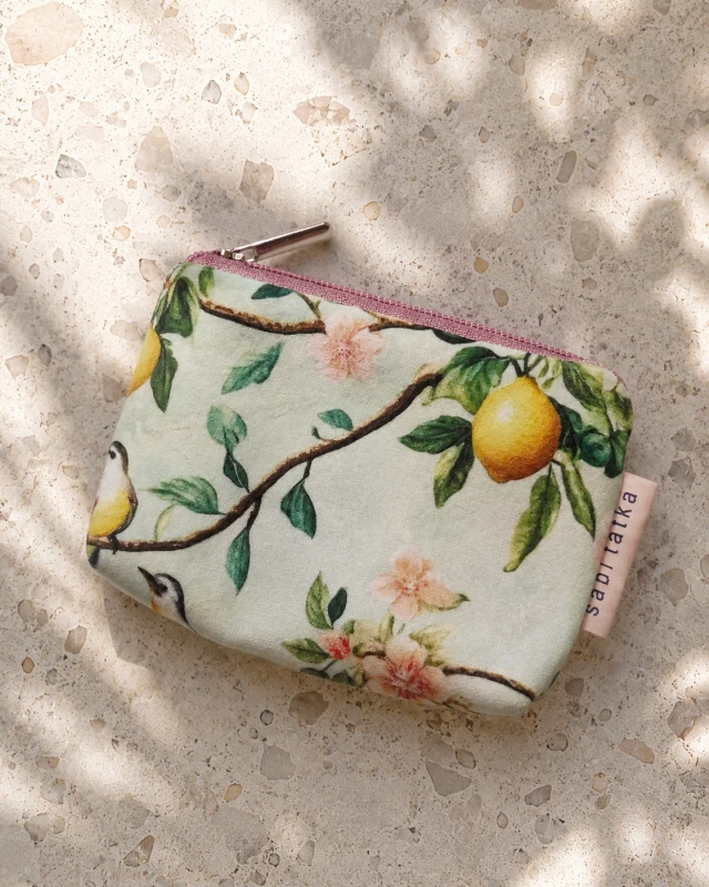 Małe etui na karty i monety w cytrusowo-kwiatowy wzór z pastelowym zamkiem. Lekkie, poręczne i stylowe – idealne do przechowywania kart, gotówki i drobiazgów. Naturalny design inspirowany śródziemnomorskim stylem.