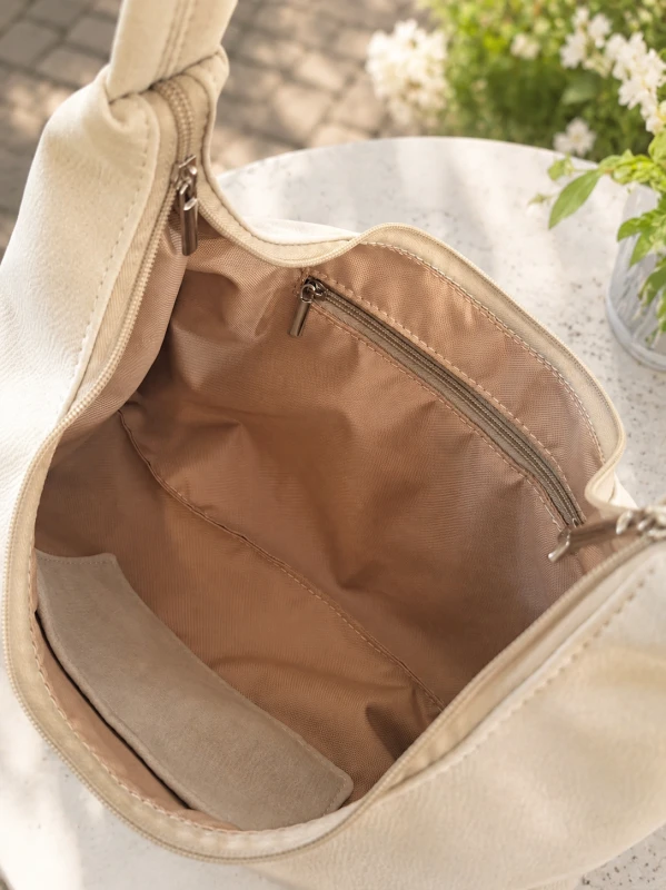 Miękka torebka slouchy z kremowego zamszu zachwyca minimalistycznym designem i pojemnym wnętrzem. Lekka, wygodna i stylowa, idealnie uzupełnia codzienne oraz eleganckie stylizacje. Ponadczasowy fason i najwyższa jakość wykonania.
