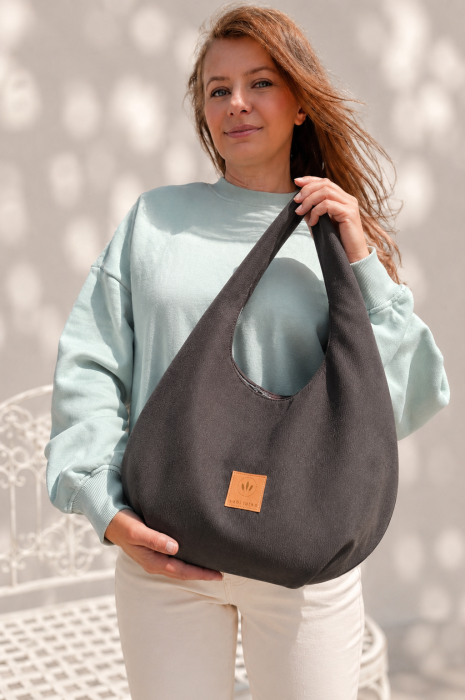 Zamszowa torebka hobo w ciemnobrązowym kolorze to połączenie minimalistycznego designu i funkcjonalności. Miękka faktura, pojemne wnętrze i wygodny pasek na ramię sprawiają, że idealnie sprawdzi się w codziennych stylizacjach casual i smart casual.