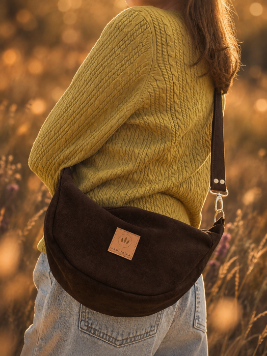 Czekoladowa nerka crossbody z miękkiego zamszu to stylowy dodatek na co dzień. Pojemna, lekka i wygodna, posiada regulowany pasek oraz praktyczne wnętrze. Idealnie uzupełni casualowe i miejskie stylizacje.