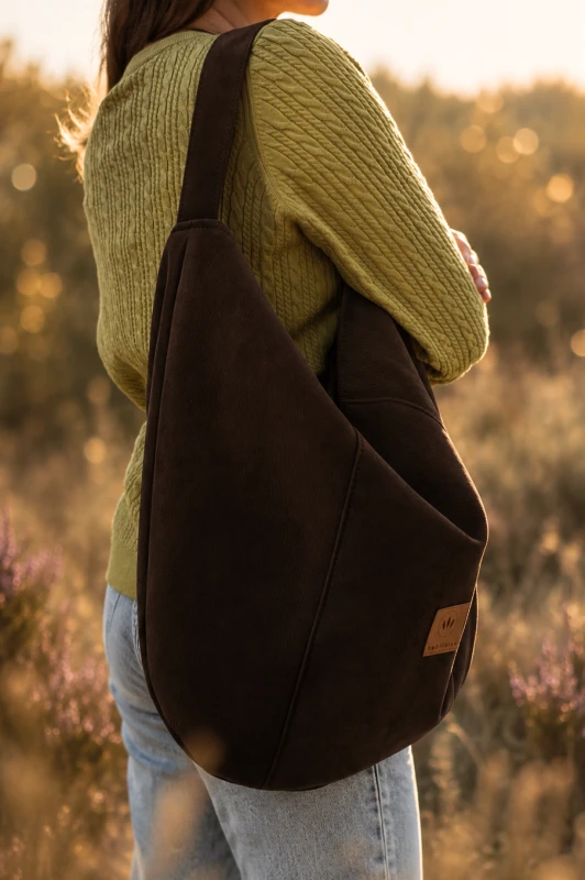 Zamszowa torba hobo w kolorze czekoladowego brązu, lekka i stylowa. Pojemna forma, minimalistyczny design i naturalna faktura sprawiają, że idealnie uzupełnia codzienne i letnie stylizacje.
